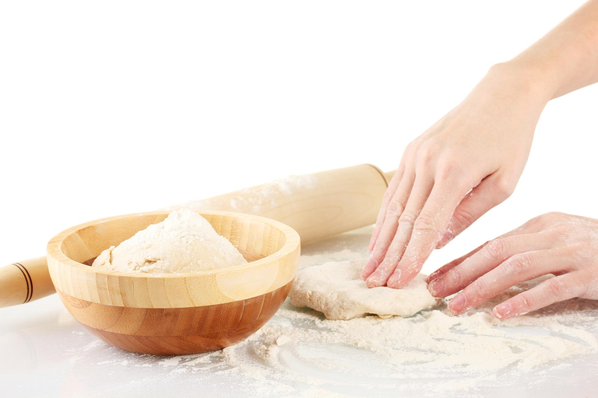 Hands kneading dough in a bright kitchen